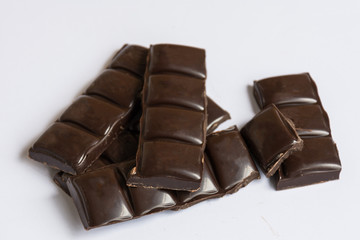 Dark chocolate pieces closeup on the white background top view.