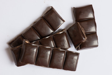 Dark chocolate pieces closeup on the white background.