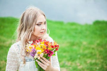Naklejka premium portrait of a blond girl with a bouquet of flowers on a lake background close-up