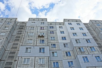 part of a high gray house with windows on the sky background