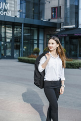 Fototapeta premium A business woman goes down the street. A girl in a business suit at the office. A wonderful girl in the city.
