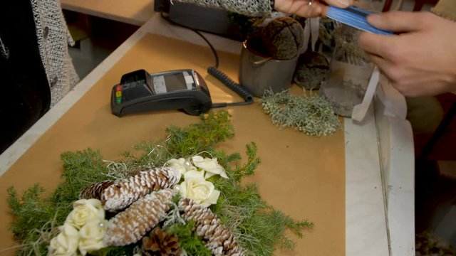 Hand offering credit card for payment at checkout in nursery