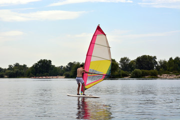 man stands on the Board in the water windsurfing