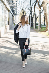 Obraz premium A business woman goes down the street. A girl in a business suit at the office. A wonderful girl in the city.