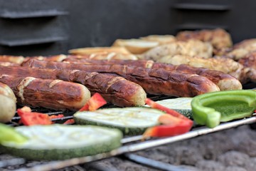  Tasty food, nutrition, culinary and barbecue concept: grilled sausages,chicken thigh and vegetables on a barbeque.