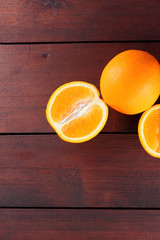 Fruits of oranges on a dark brown wooden background, halves of oranges on wooden boards. Copy space. Orange fruits for vegans. Citrus for breakfast