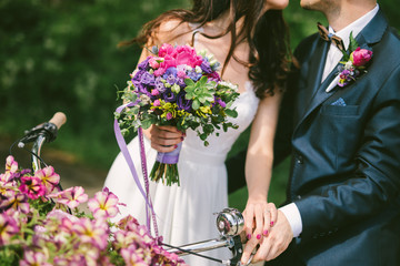 nice wedding bouquet in bride's hand and groom with bicycle