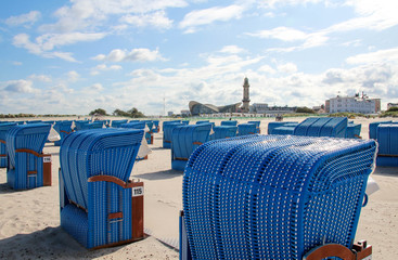 Strandkörbe am Strand von Warnemünde (Deutschland) mit einem Leuchtturm im Hintergrund