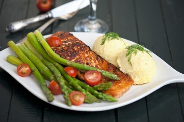 Baked salmon garnished with asparagus and tomatoes with herbs and mashed potatoes