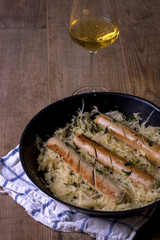 Salchichas en una sartén con una copa de vino blanco Bratwurst