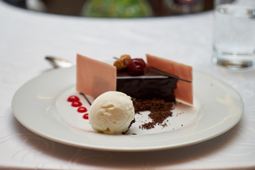 Black forest slice cake with cherry, vanilla ice-cream, chocolate dirt on a white plate, close-up. Tradidional delicious sweet dessert food 