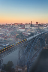 Famous bridge Ponte dom Luis covered with morning fog during sunrise in Porto, Portugal