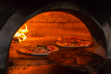 Original neapolitan pizza margherita in a traditional wood oven in Naples restaurant, Italy