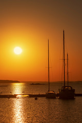 Silhouette of sailboats moored at an marina during a golden sunset in the swedish archipelago