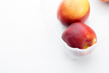 Pfirsiche in Plastikschale, heller Hintergrund