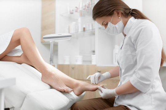 Brunette Female Podiatrist Making Polish And Cleaning Procedure For Foot.