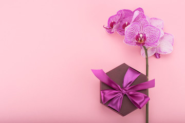 Pink orchid flowers and hexagonal gift box with bow. Flat layout