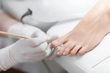 Wall murals Pedicure Specialist in beauty salon making french pedicure for female client.