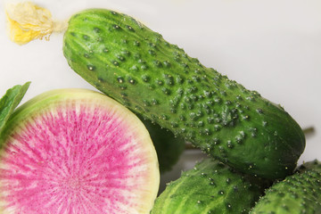 A lot of cucumbers in the basket. Cucumbers in a large wicker basket. Vegetables in wicker vessels for diet. A lot of cucumbers in a wicker box. Sliced cucumbers on a cutting board.