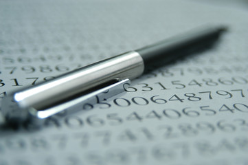 Math still life photos. Silver ballpoint pen on a page of numbers, shallow depth of field shot with...