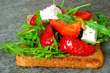 Toast with arugula, strawberries and soft white cheese. Fashion fitness food. Stylish snack.