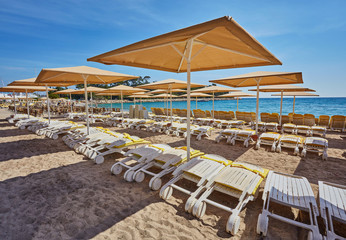 Umbrellas and empty beach chairs on the beach near blue sea water, Kemer, Turkey