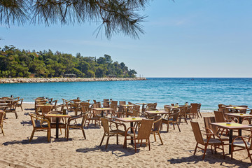 Tables and chairs on terrace in outdoor restaurant with view in Kemer, Turkey.
