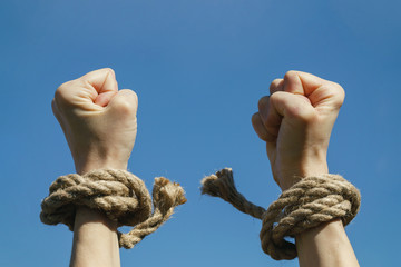 Hands free from shackles are stretched to the blue sky. Feeling of freedom