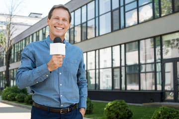 smiling male mature newscaster with microphone
