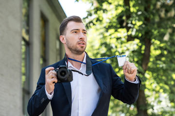 photojournalist in formal wear with digital photo camera and press pass