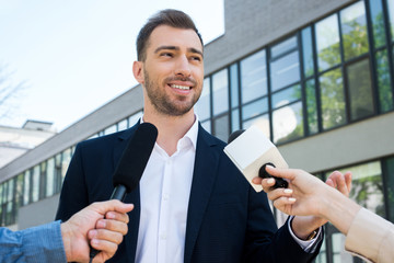 Fototapeta premium two journalists interviewing successful businessman with microphones
