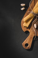 top view of tied spaghetti with garlic on wooden cutting board