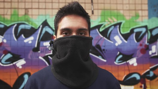 Portrait of young man graffiti artist on graffiti wall background, close up