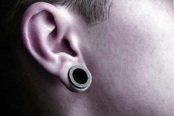 Round earrings of black tunnels in the ears close-up.