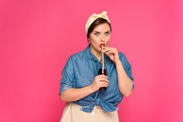 beautiful pin up woman drinking refreshing beverage and looking at camera isolated on pink
