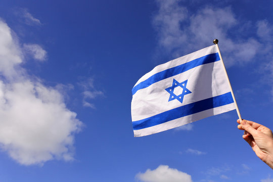 Woman wave flag of Israel against blue sky and white clouds on Israels 70's independent day.