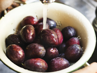 Organic plums being washed under running water food photography recipe idea