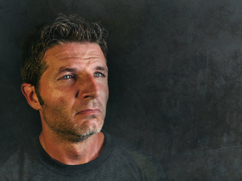 young sad and devastated man looking far away thoughtful and pensive feeling stressed and lost suffering pain and depression isolated on black