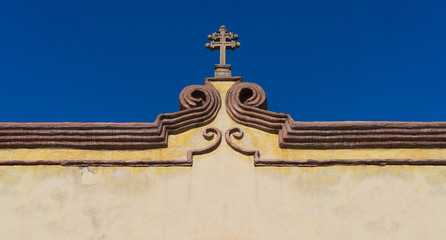 Mexican colonial cross on cornice, old house facade in Queretaro Mexico.