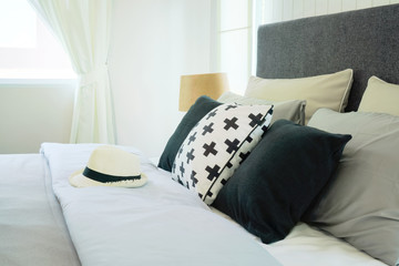 Hat on bed with pillows in stylish bedroom interior