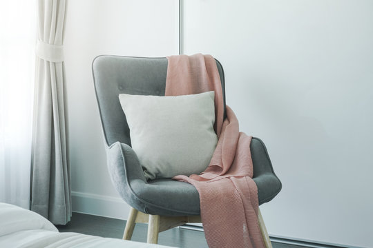 Pink scarf and beige pillow on gray armchair at the corner of living room