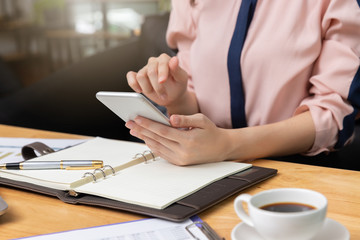 Business and finance concept, Businesswoman using smart phone and discussing sale analysis Chart in coffee shop