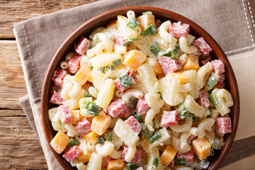 hearty Hawaiian salad with pasta, ham, pineapple, onion, cheddar cheese dressed with mayonnaise close-up. horizontal top view