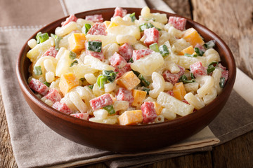 Hawaiian cuisine: salad with pasta, ham, pineapple, onion, cheddar cheese with mayonnaise close-up....