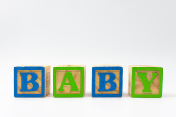 Wooden toy blocks spelling baby on white background.