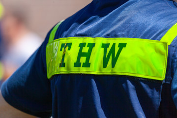 German technical emergency service sign on a vest from a man. THW, Technisches Hilfswerk means technical emergency service.