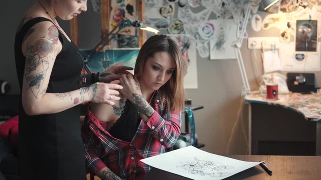tattoo artist discusses with a client sketch tattoo. tattoo master in home Studio