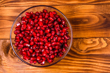 Seeds of the garnet fruit in glass bowl on wooden table. Top view
