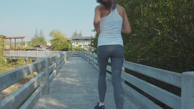 Young woman jogging on mangroves forest path. Steadicam shot in slow motion