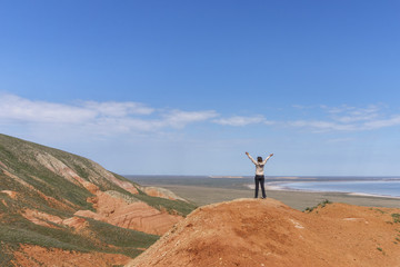 Obraz premium Young active woman standing on top of a mountain, raising her hands to the sky